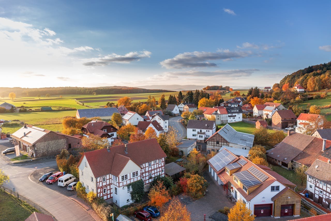 Why-Choose-Us-02 charming aerial view of a rural village in autumn with vivid colors and clear skies.