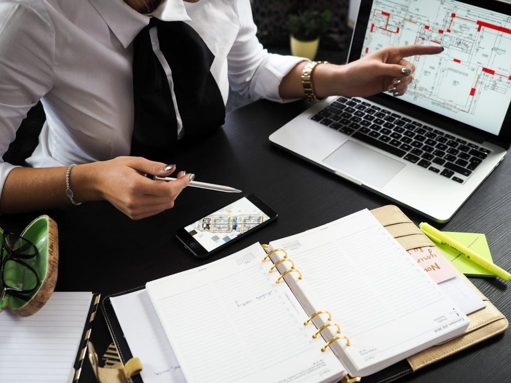 a business professional working on real estate project plans using multiple devices in an office setting.