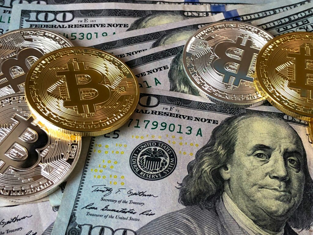 A CloseUp Photo Depicting Bitcoin Coins On Top Of Us Dollar Bills, Symbolizing Finance And Cryptocurrency.